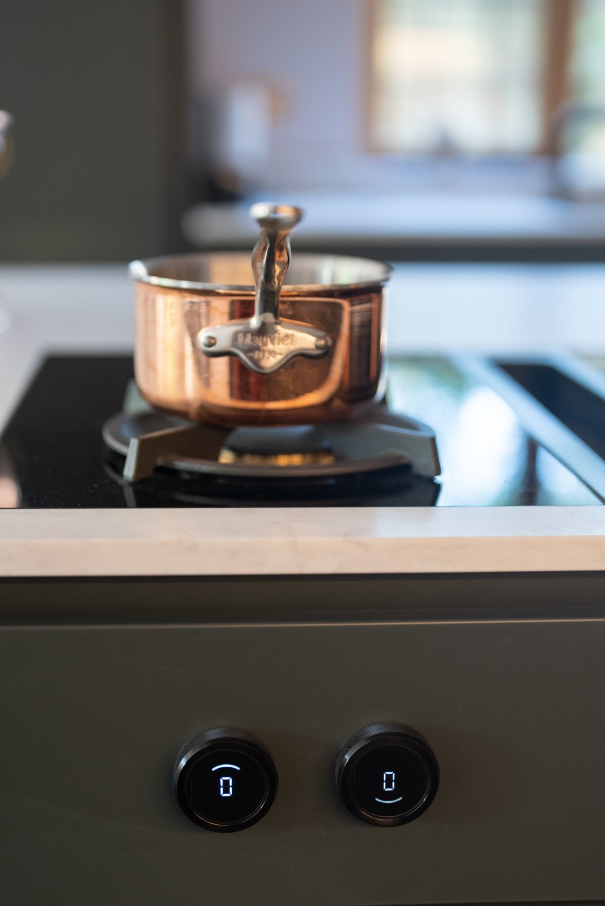 a copper pan sits atop a gas hob by bora with illuminated dials underneath