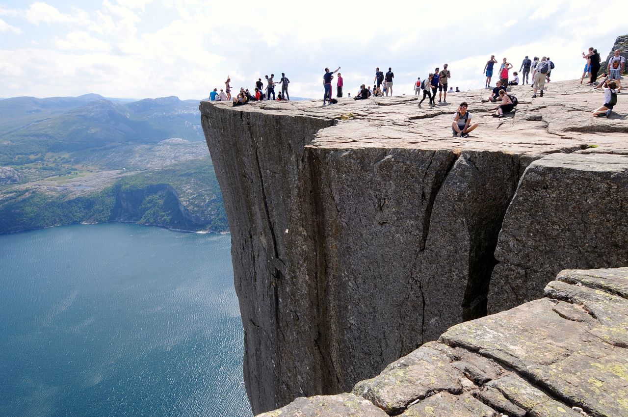 Preikestolen sett fra siden, med masse folk på kanten av fjellformasjonen.