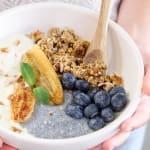 Bol pour le petit-déjeuner avec du pudding de chia, des morceaux de pomme, du granola bio et une cuillère de granola à tartiner