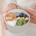 Bol pour le petit-déjeuner avec du pudding de chia, des morceaux de pomme, du granola bio et une cuillère de granola à tartiner