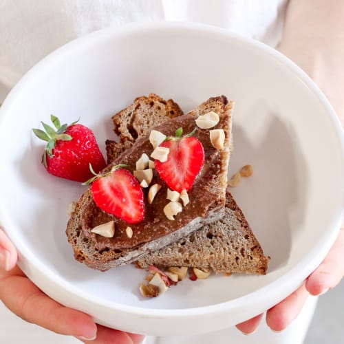 Bol pour le petit-déjeuner avec du pudding de chia, des morceaux de pomme, du granola bio et une cuillère de granola à tartiner