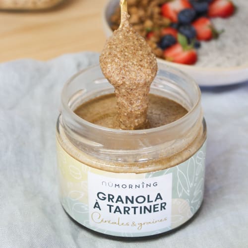 Bol de pudding de chia avec des quartiers de pommes, du granola maison et une cuillère de granola à tartiner