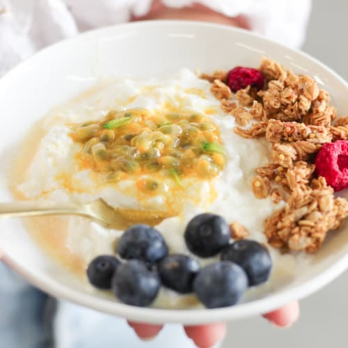 Bol pour le petit-déjeuner avec du pudding de chia, des morceaux de pomme, du granola bio et une cuillère de granola à tartiner