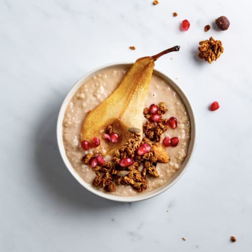 Porridge crémeux avec une poire cuite et du granola bio à la cannelle, aux amandes et aux noisettes