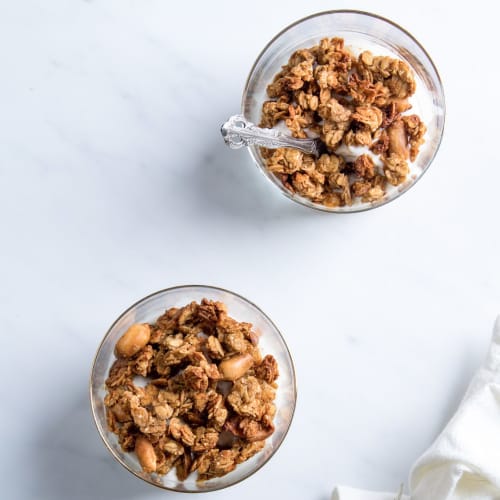 Bol pour le petit-déjeuner avec du pudding de chia, des morceaux de pomme, du granola bio et une cuillère de granola à tartiner