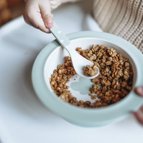 Bol de pudding de chia avec des quartiers de pommes, du granola maison et une cuillère de granola à tartiner