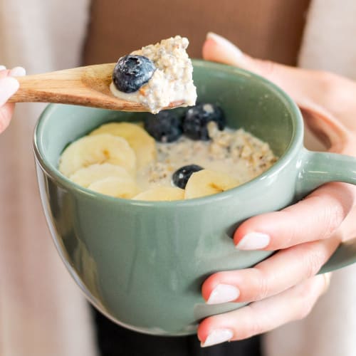 Bol pour le petit-déjeuner avec du pudding de chia, des morceaux de pomme, du granola bio et une cuillère de granola à tartiner