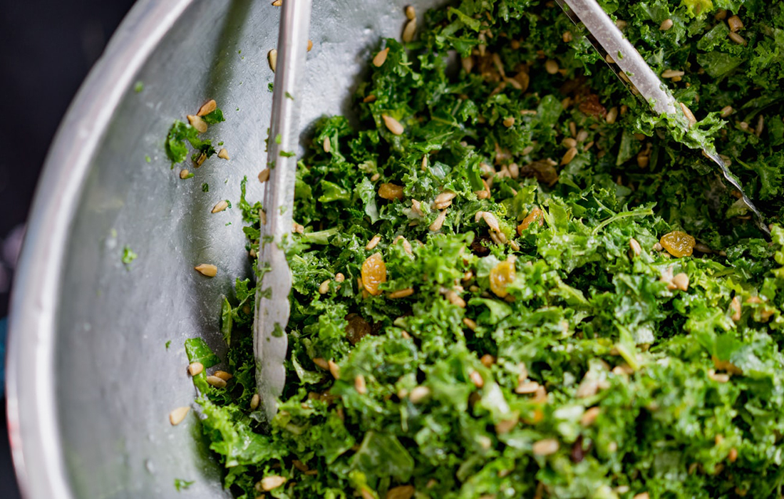 dark leafy super greens in a bowl with tongs