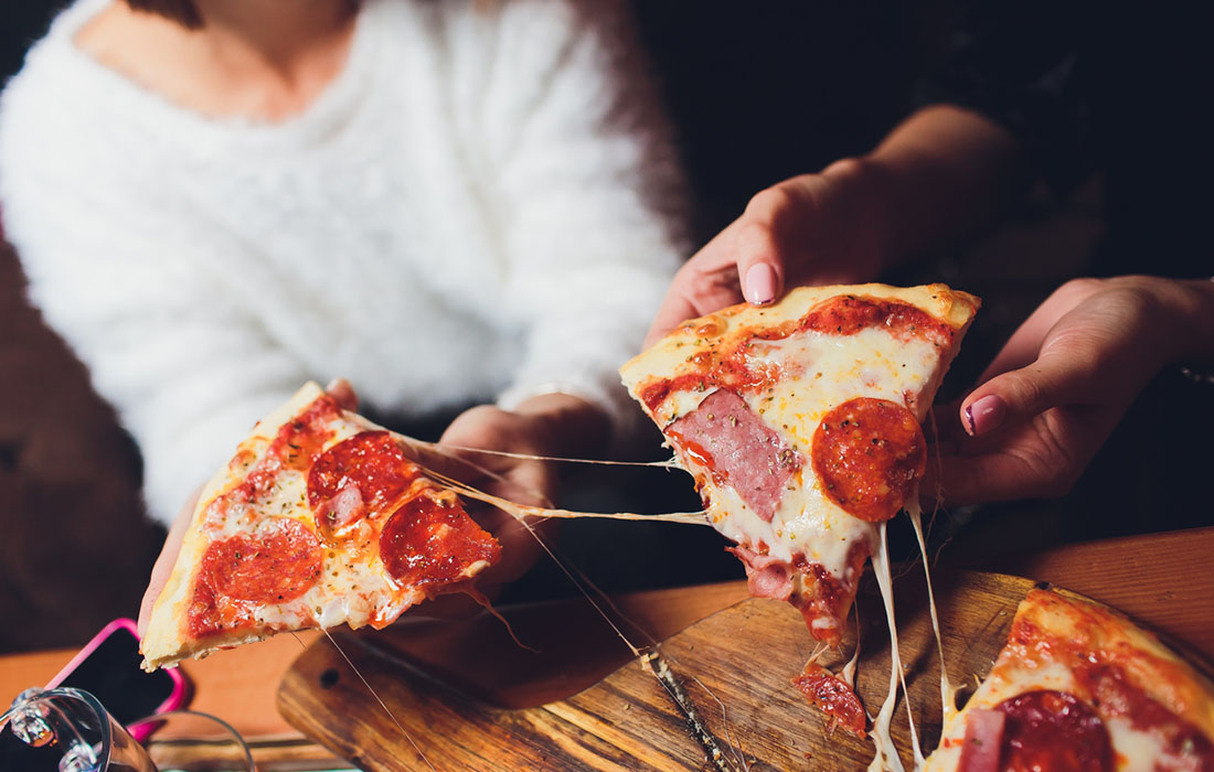 Friends seperating pizza slices with their hands