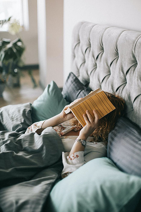 woman lying down with book over her face