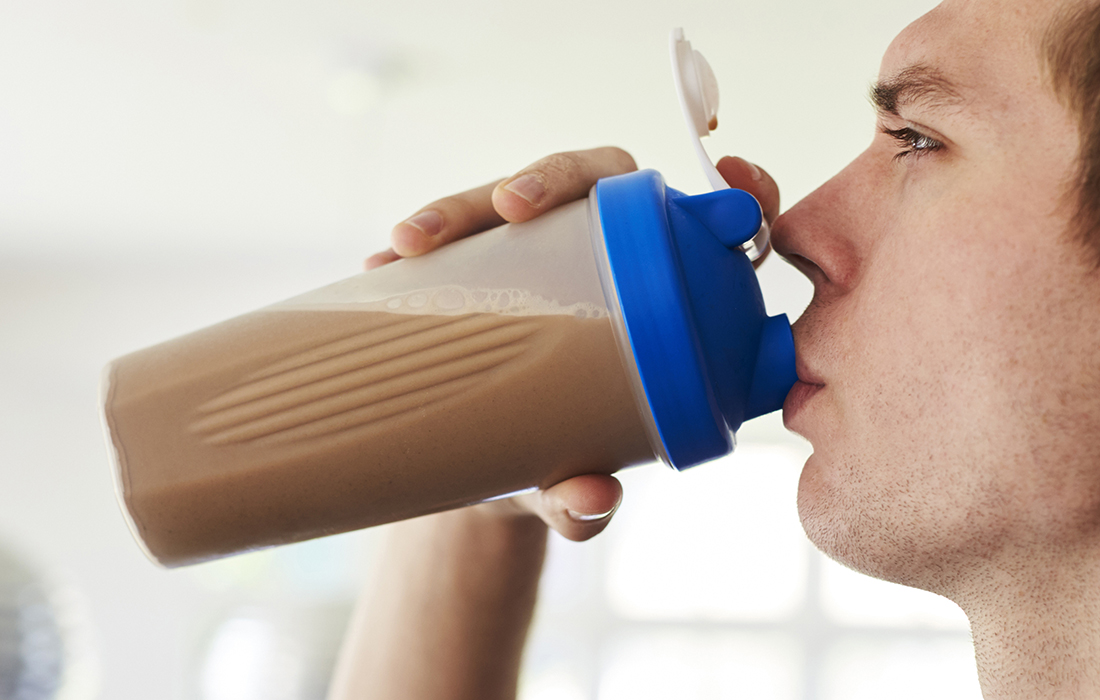 Man drinking a chocolate protein powder in a shaker