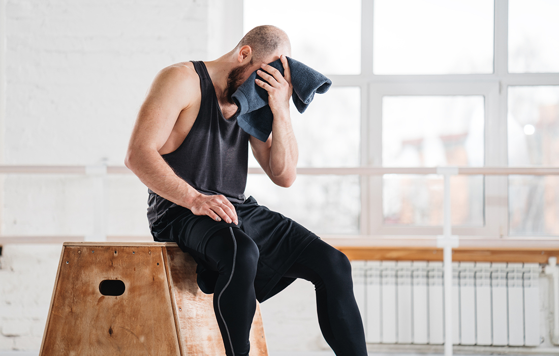 athlete in gym wiping sweat off forehead