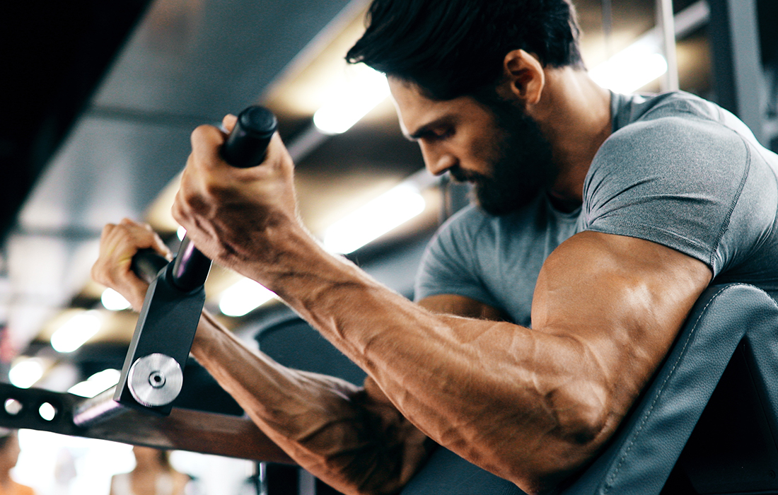man doing preacher curl at gym