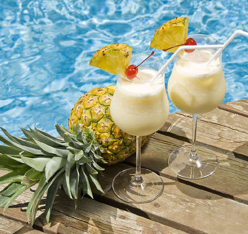 pineapple and two mocktails drinks by a pool
