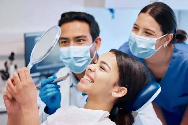 Image of dental professionals collaborating with a patient and smiling at Madison Oral Surgery & Dental Implants.