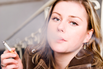 A woman smoking a cigarette and damaging her oral health. A woman smoking a cigarette and damaging her oral health.