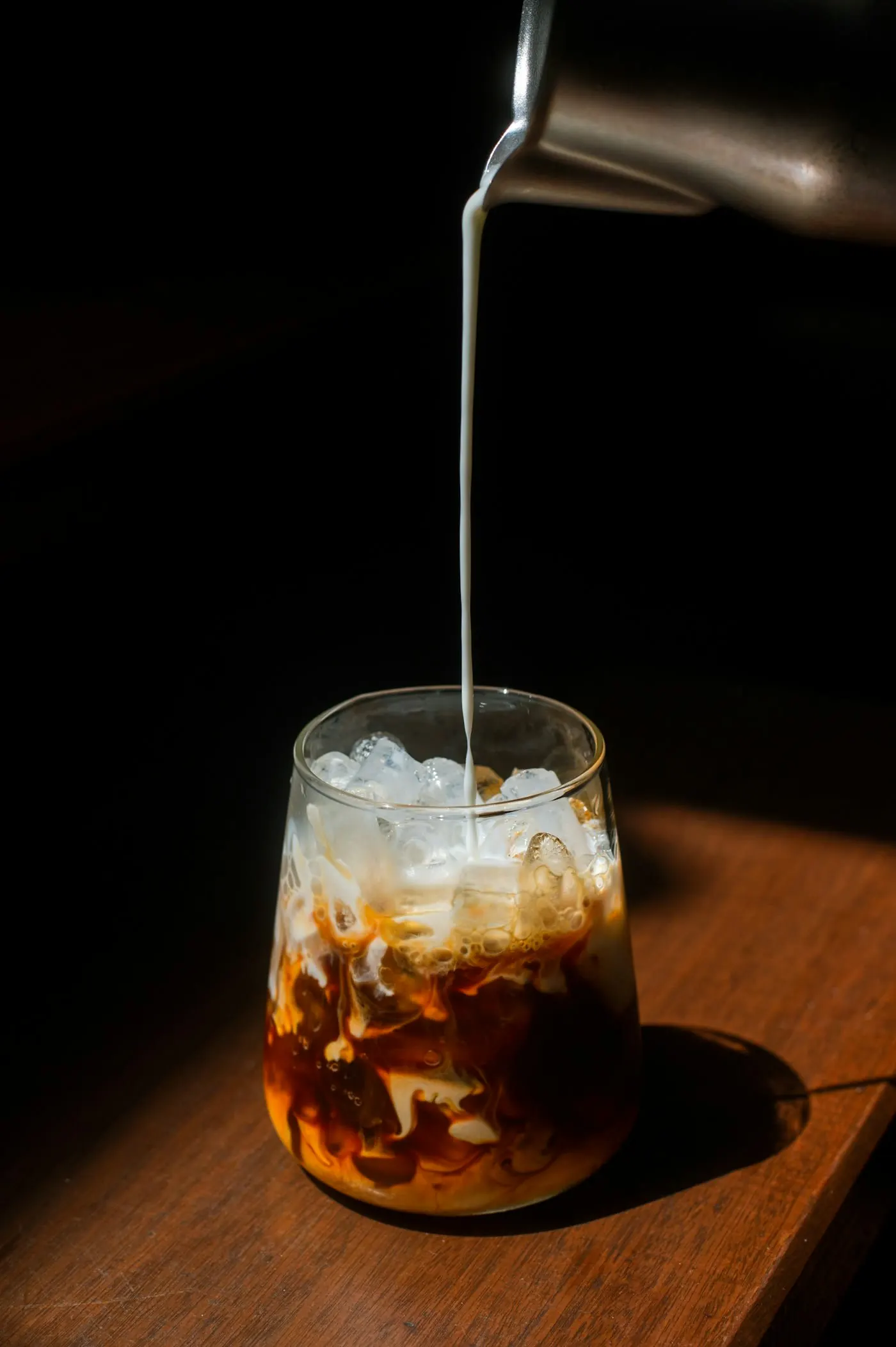 Rich milk swirling into iced coffee at PANOVA Café