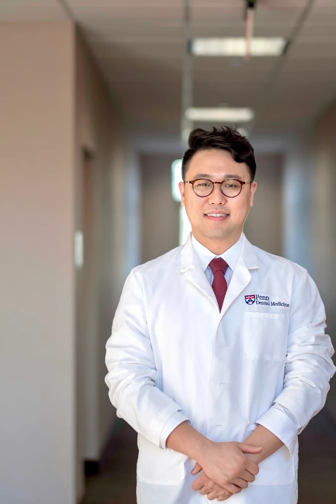 Dr. Chung wearing a white dental coat in a modern dental-office hallway