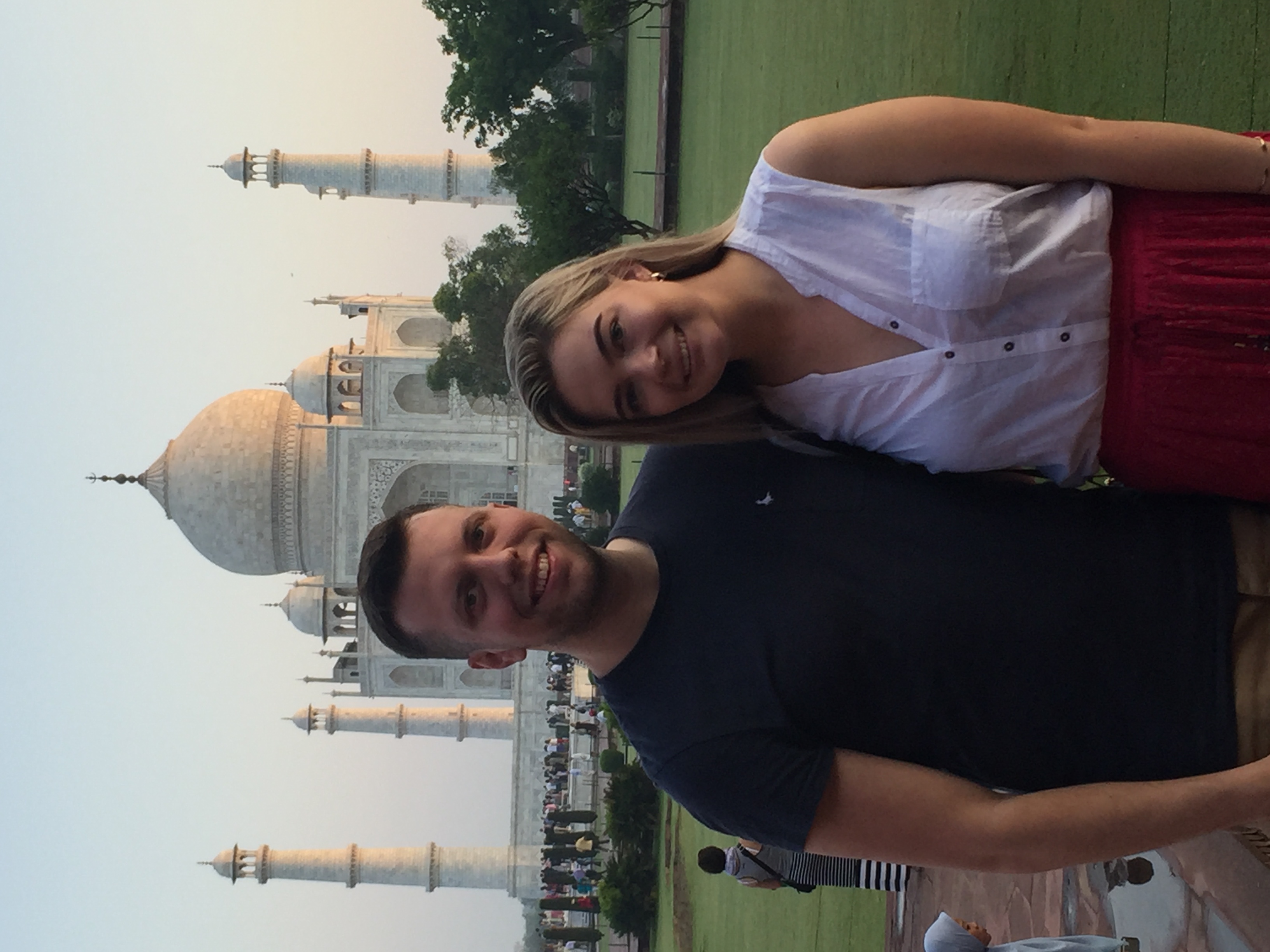 A smiling couple posing together during a tour of the white marble Taj Mahal mausoleum in Agra, India.