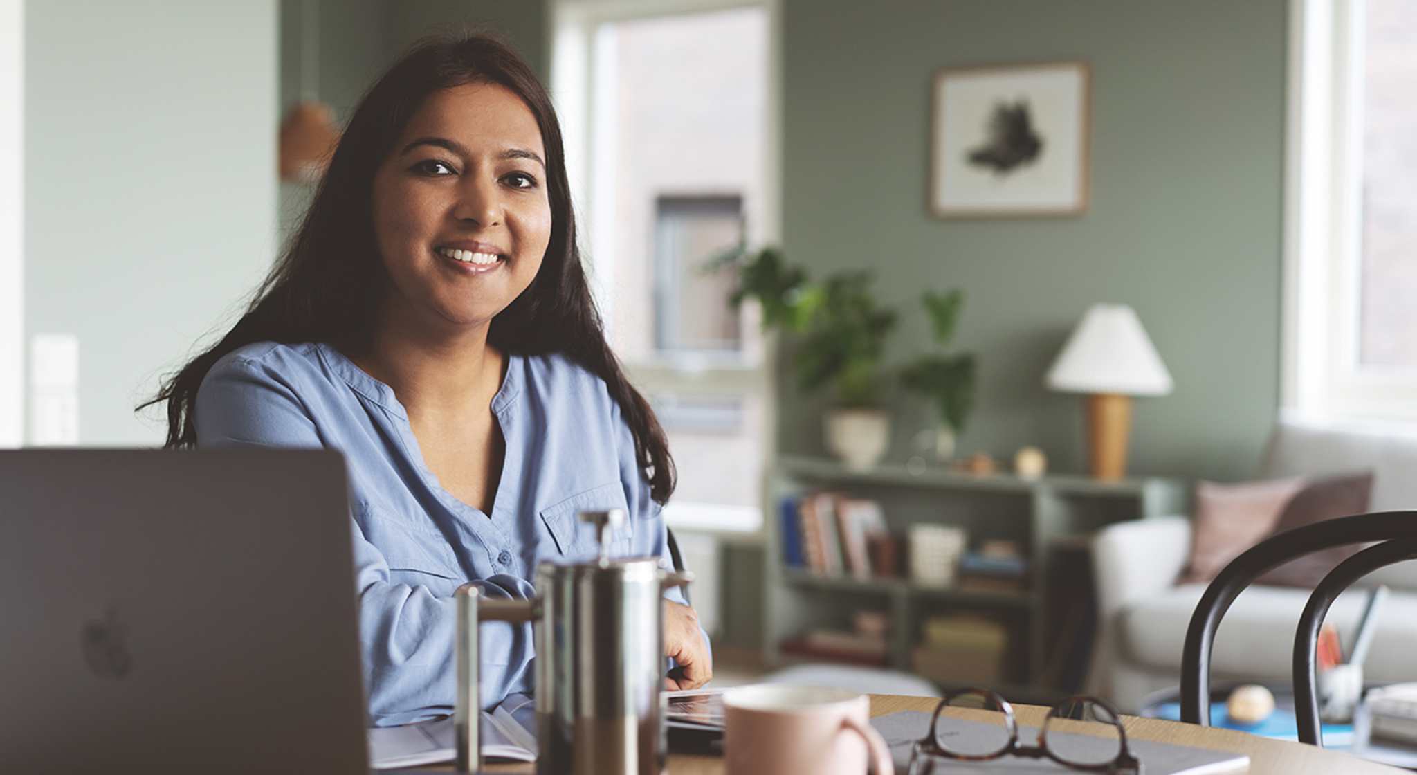 Ei dame sitter ved bordet og jobber på datamaskinen sin.