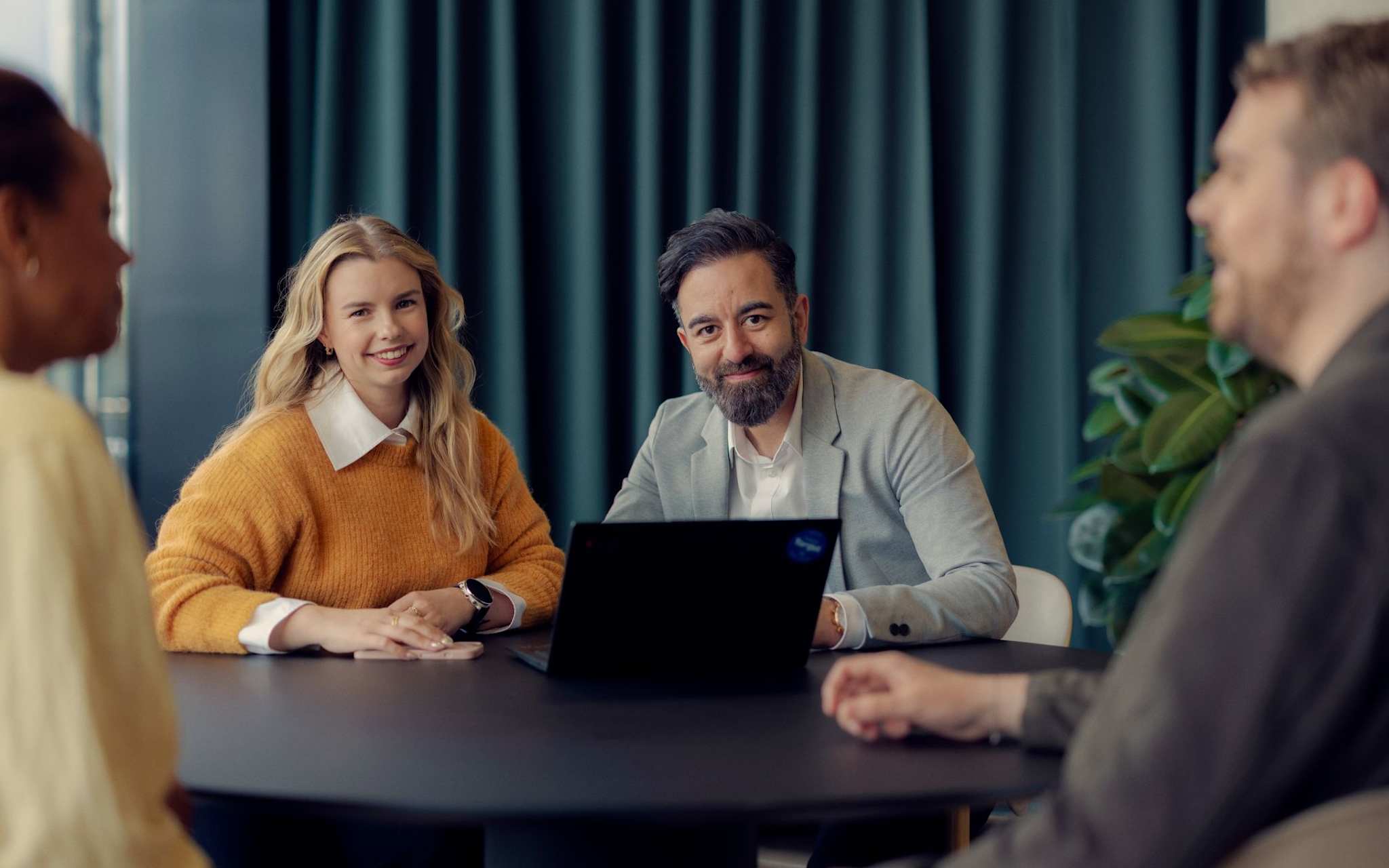 Fire personer sitter i et styremøte.