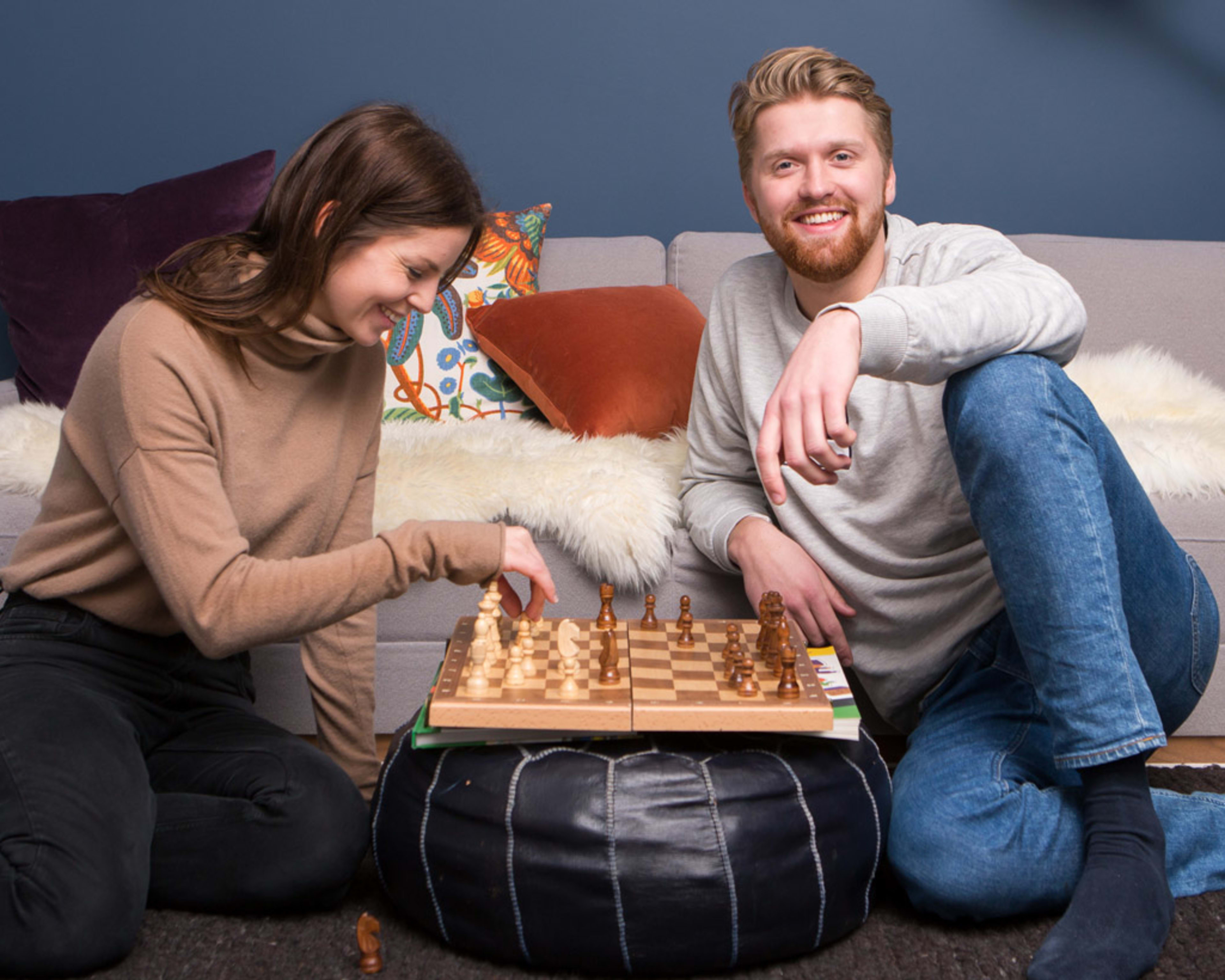 Ungt par sitter på gulvet og spiller sjakk