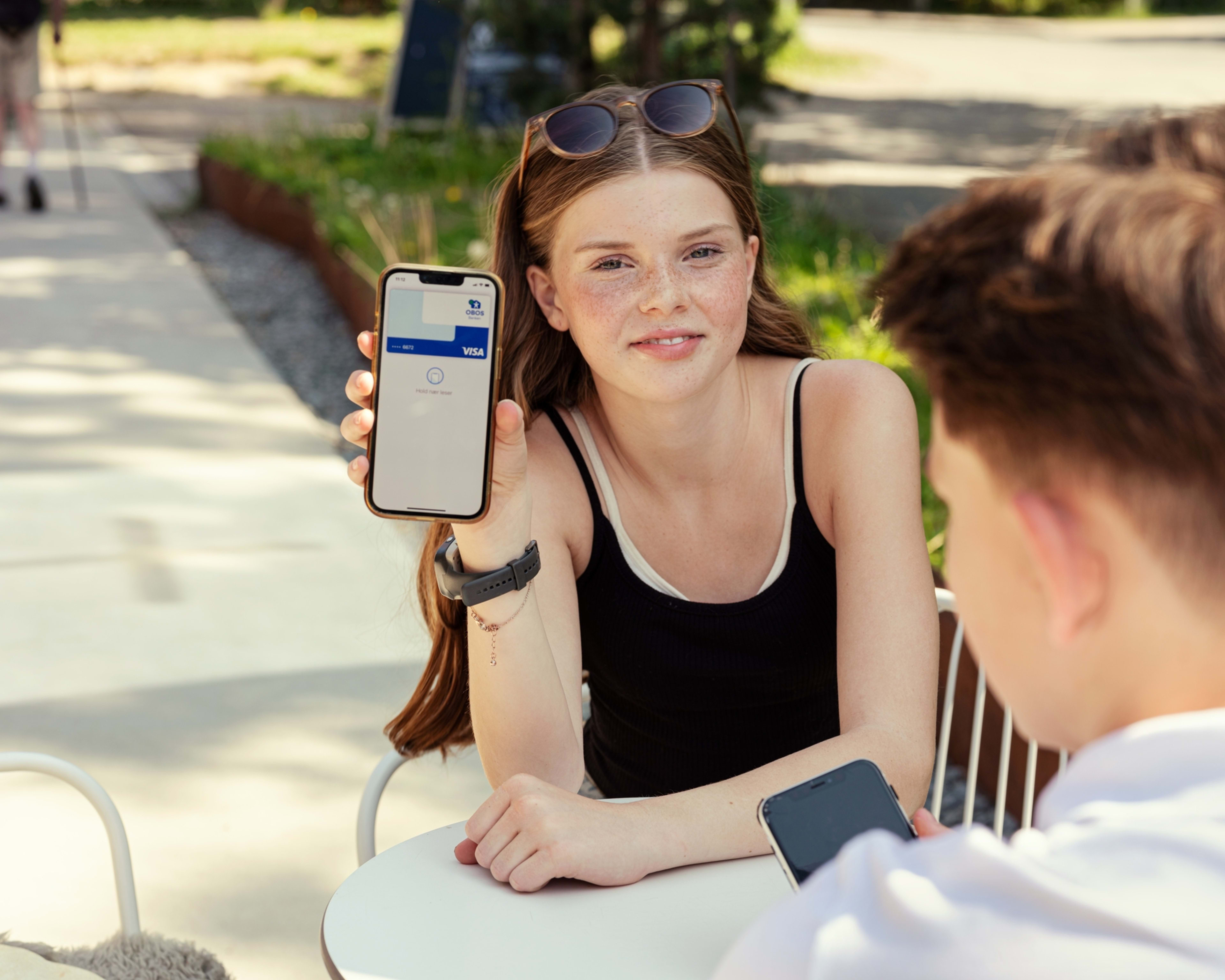 Jente som viser frem apple pay på telefonen sin