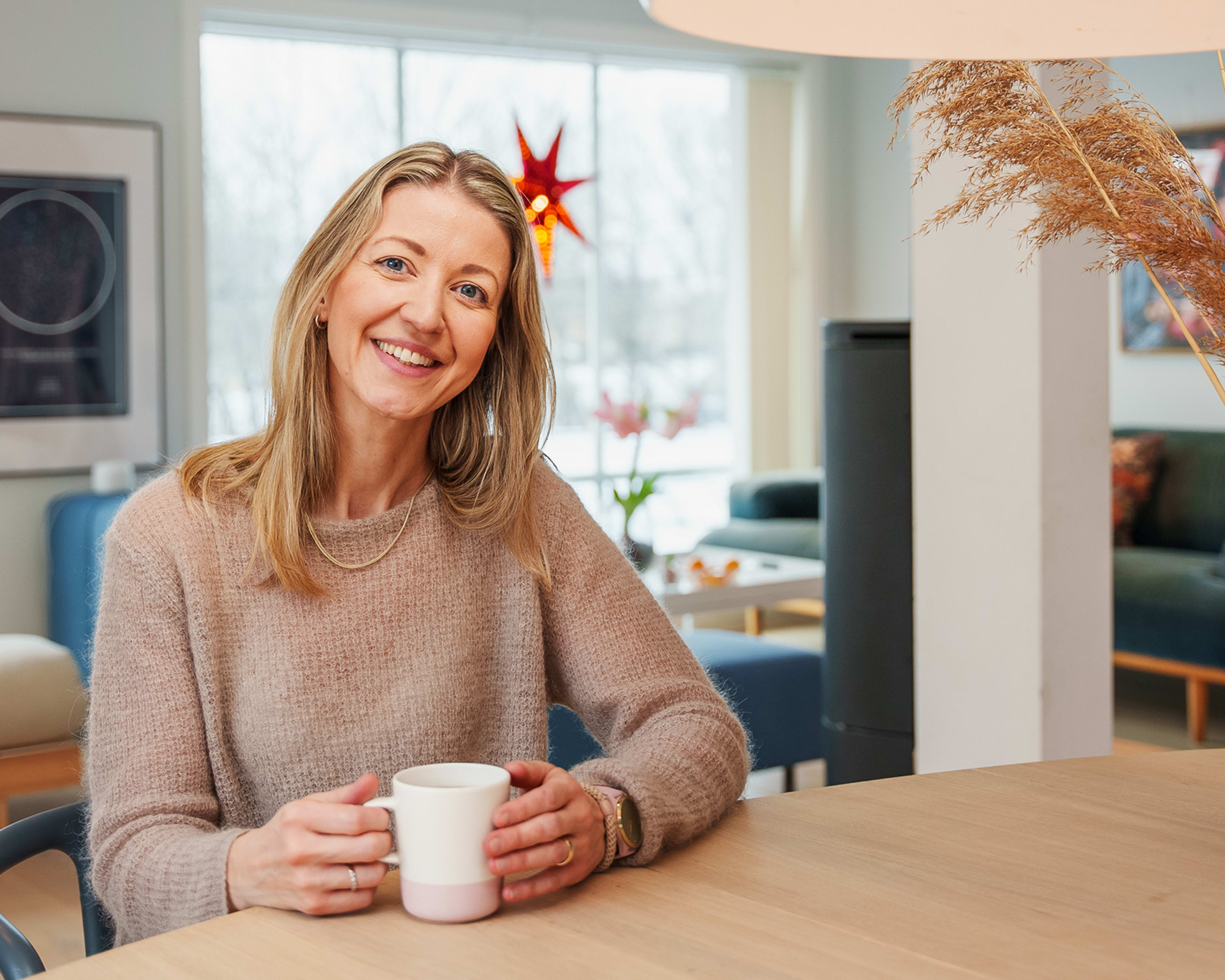 Forbrukerfrue, Kjersti Grønseth, sitter ved spisebordet hjemme. Foto.