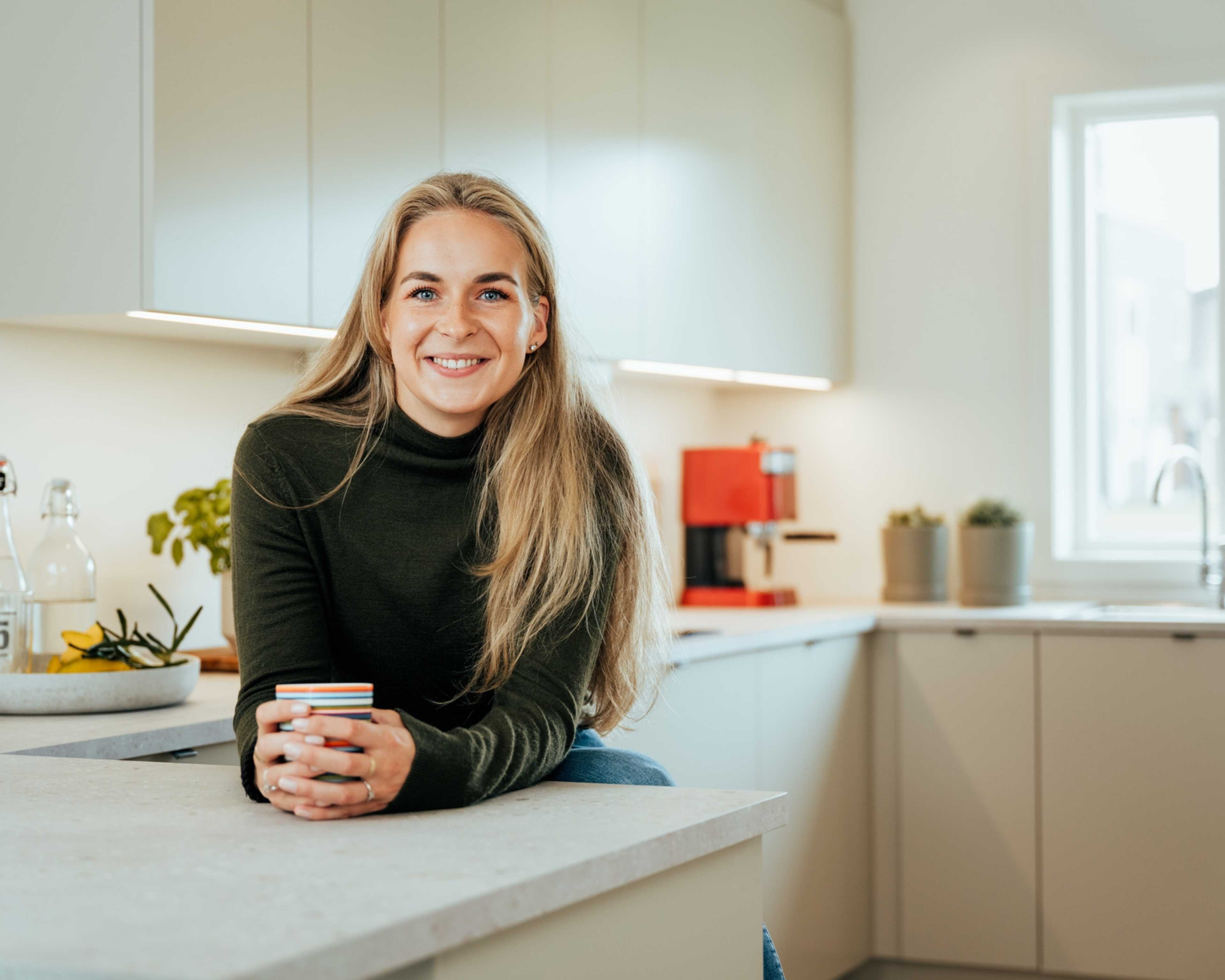 Smilende kvinne på kjøkken i leilighet