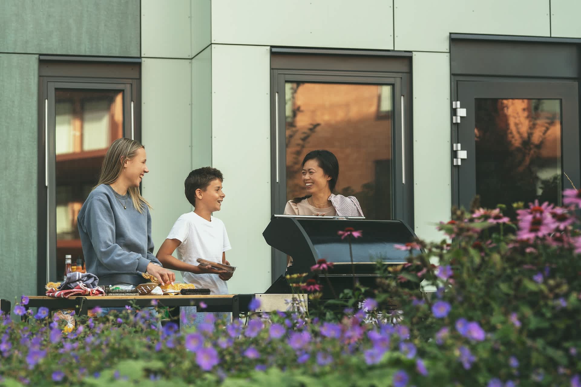 En familie står på terrassen og griller