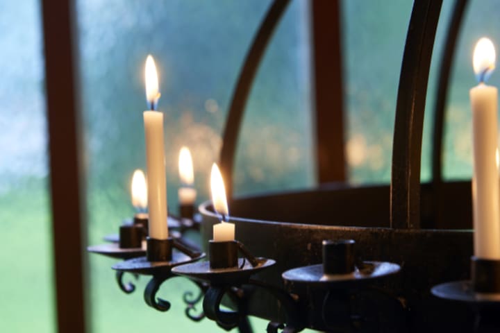 En stor lysestake med påtente stearinlys. Foto.