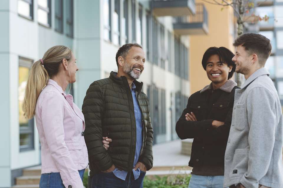 Fire naboer som snakker utenfor hjemmene sine.