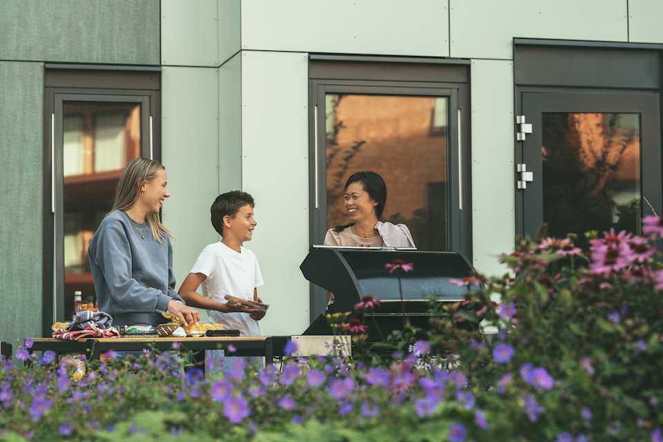En familie står på terrassen og griller