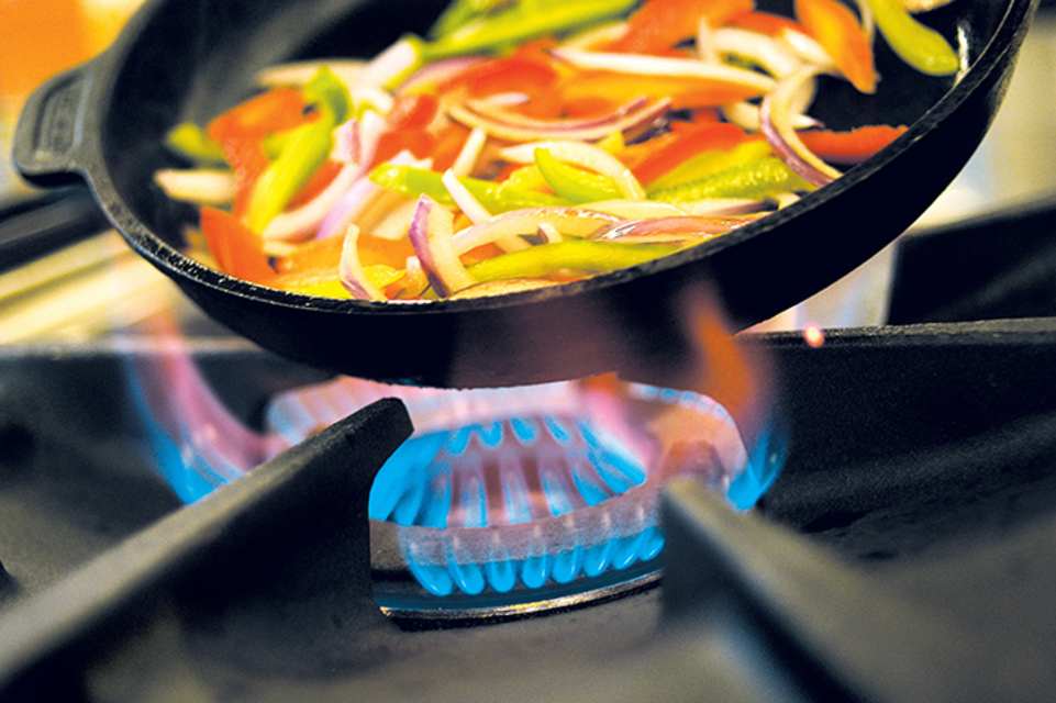 Noen lager mat på en gasskomfyr.