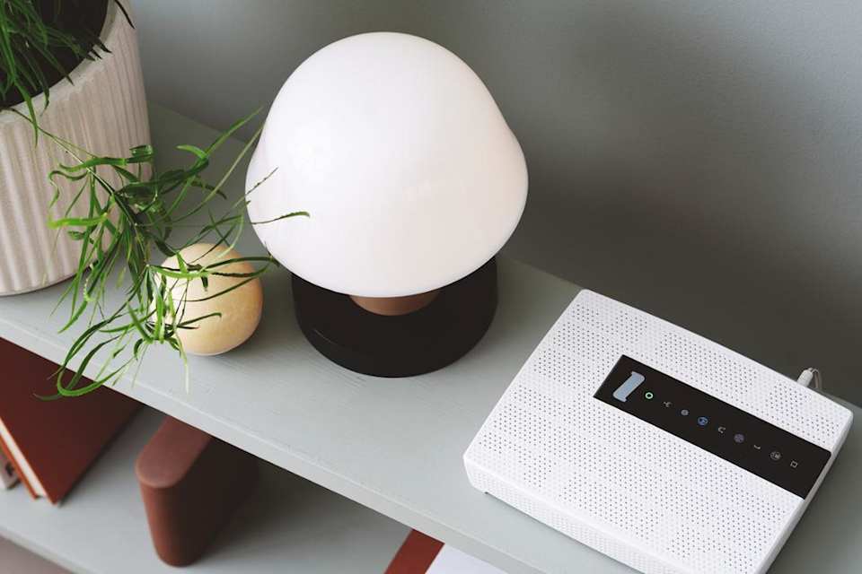 Foto av et konsollbord med et modem, lampe, noen bøker og noen planter.