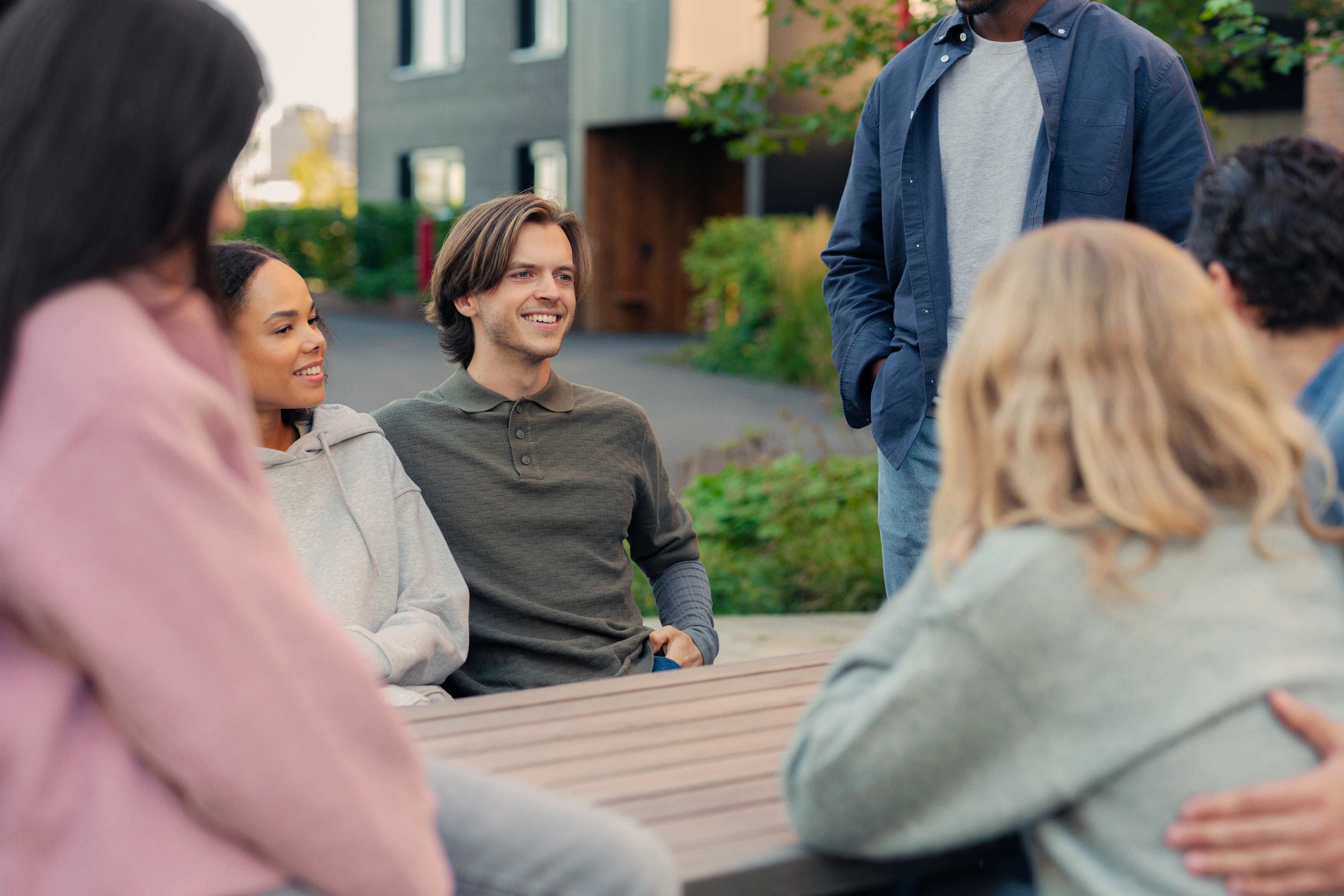 Flere personer sitter ved et bord i et uteområde i et borettslag.