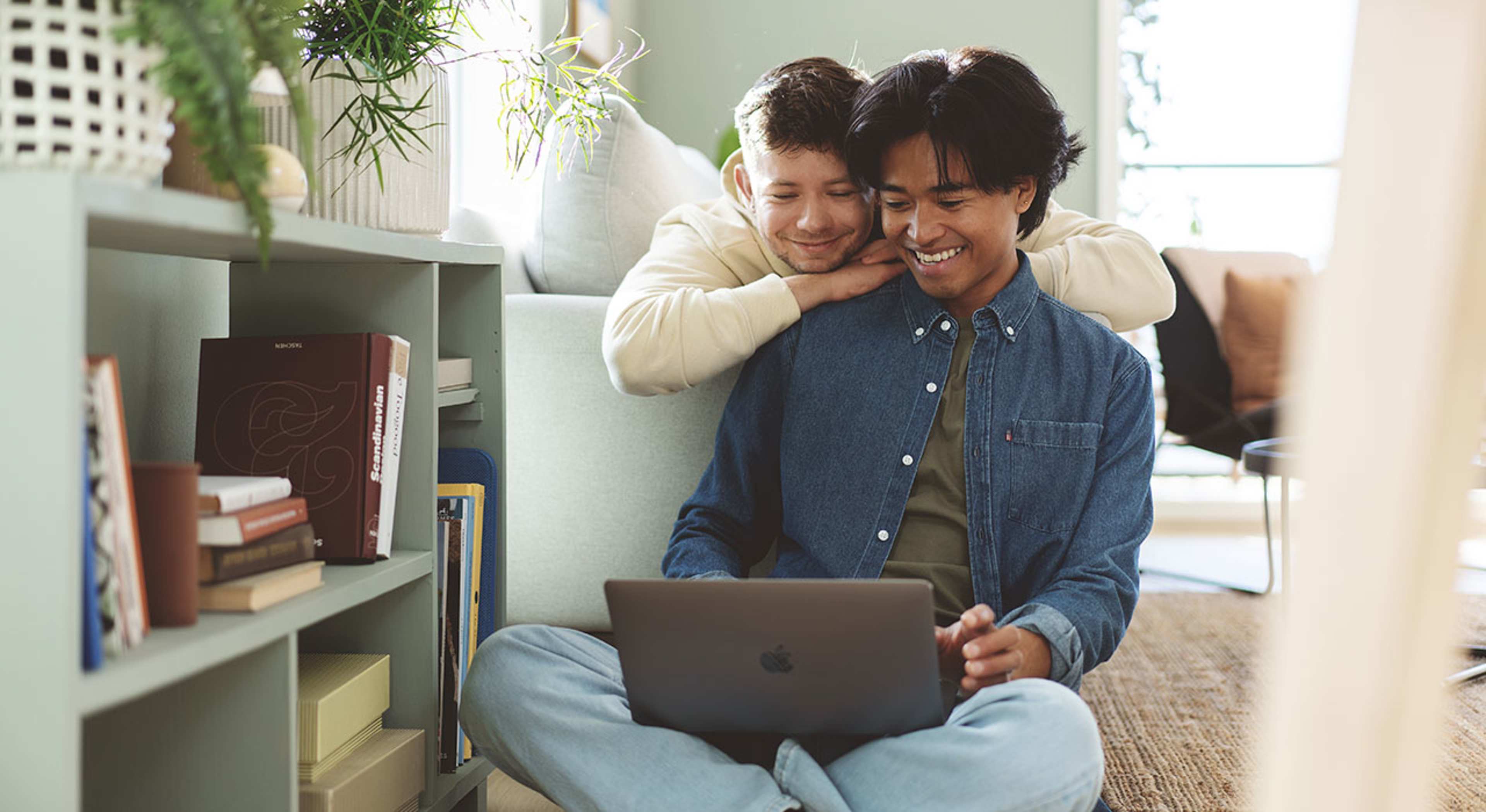 Ungt par ser på laptopskjerm og smiler