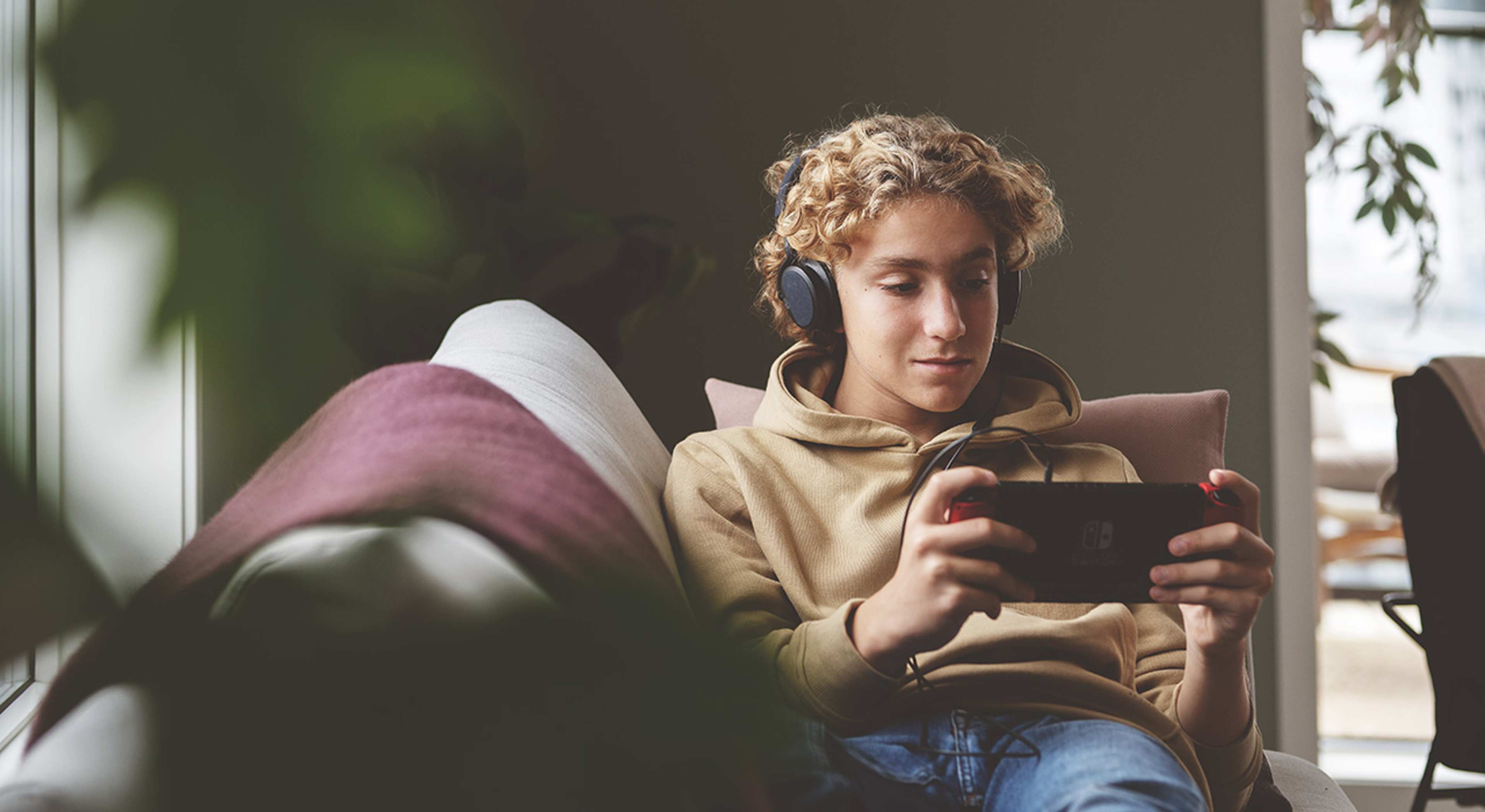 Gutt spiller på Nintendo Switch og smiler.