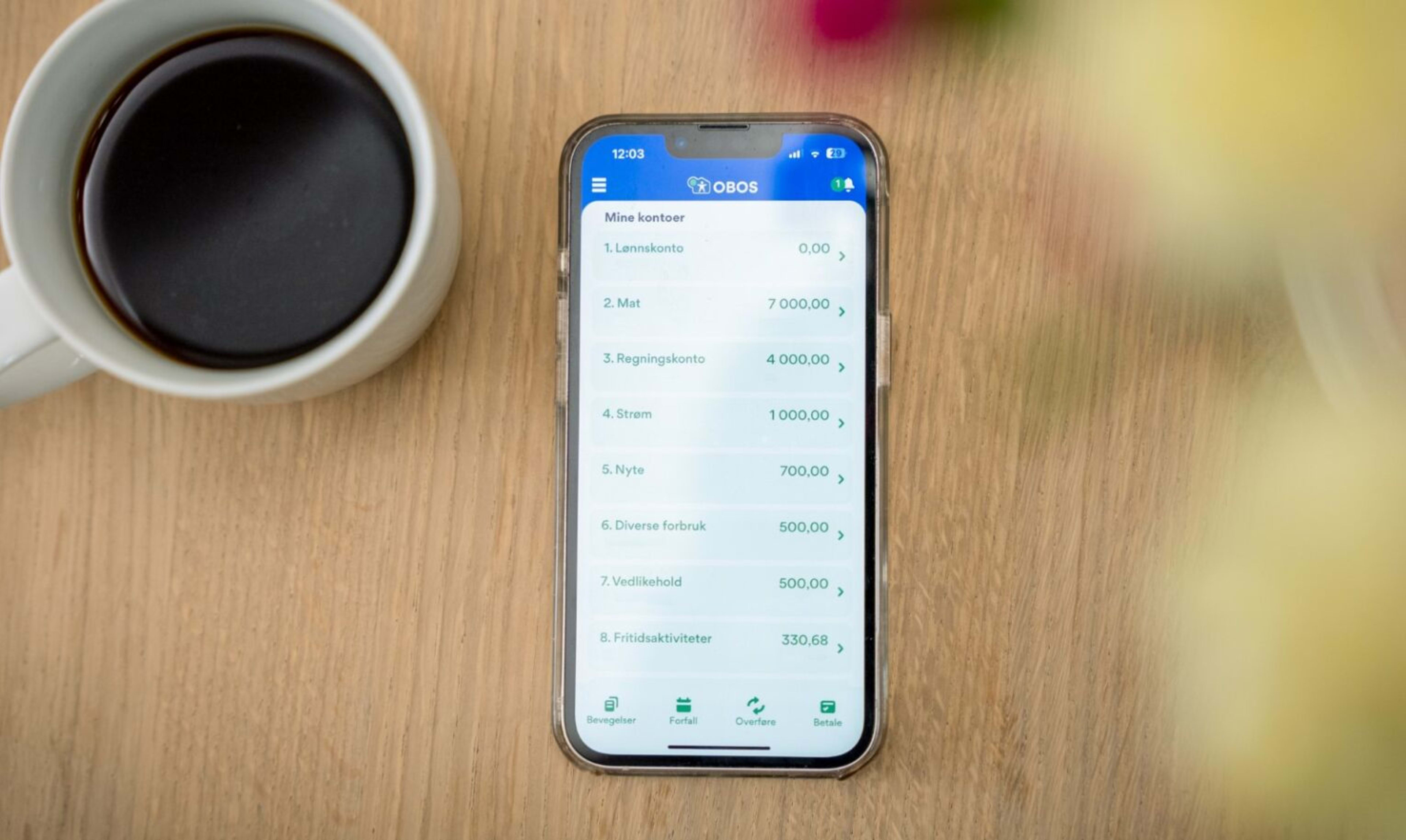 En iPhone på et bord, med en liste med kontoer i OBOS-bankens nettbank på skjermen