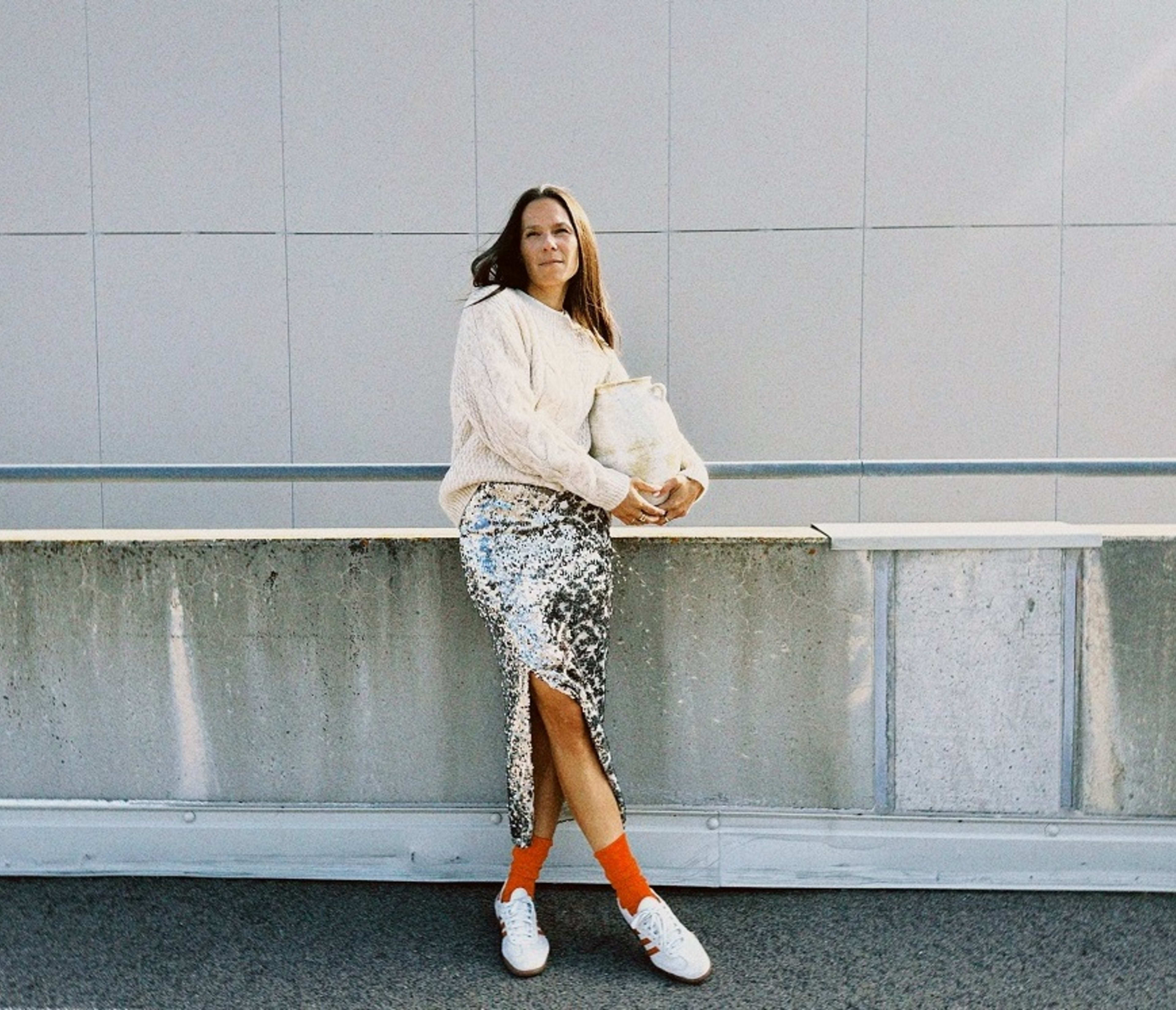 dame i hvit strikkegenser, sølvfarget paljettskjørt og hvite sneakers