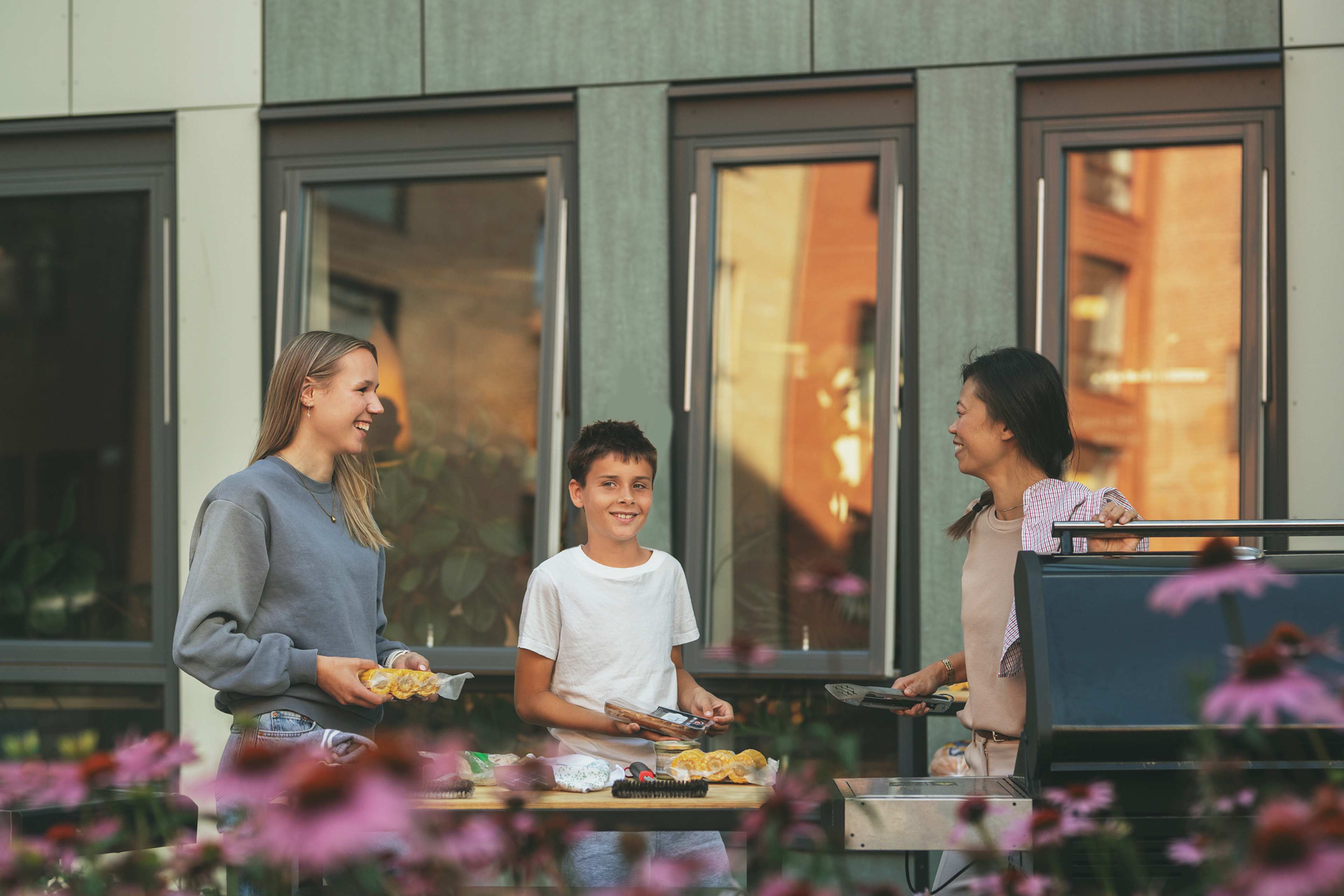 Tre beboere i et borettslag er samlet i bakgårdens fellesområde for å grille mat