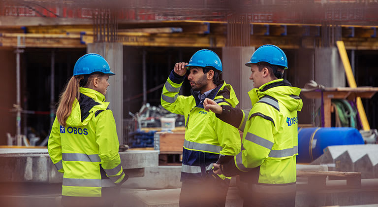 Tre arbeidere på en byggeplass.