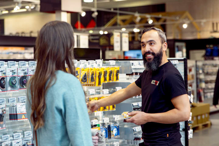 En mannlig ansatt i monter hjelper en kunde i butikken