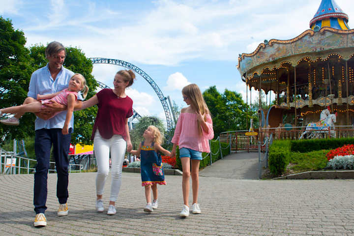 Flere barn kjører karusell på Tusenfryd. Et barn smiler fra øre til øre mens han sitter på en motorsykkel.
