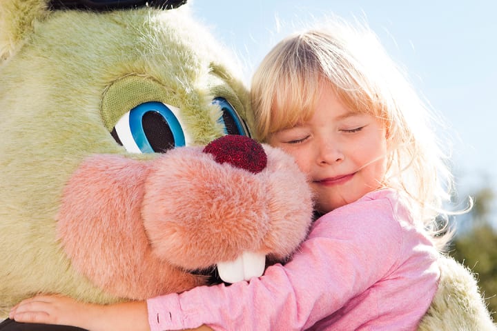 Liten jente som klemmer Liseberg maskoten i sommerdag