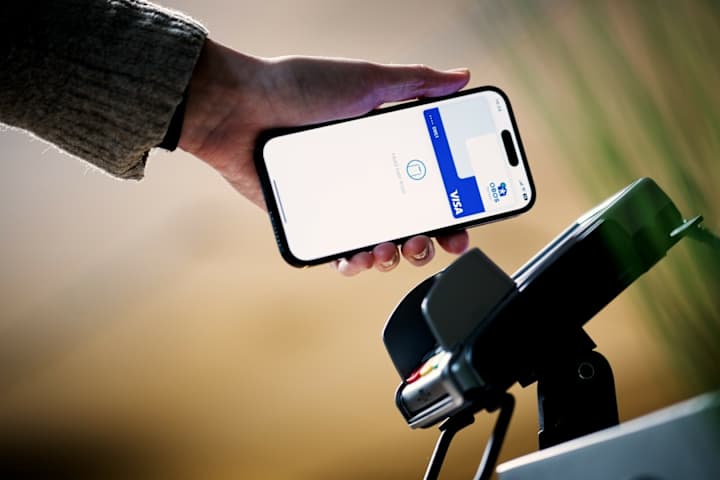 En hånd som bruker mobilen sin til å betale med Apple Pay