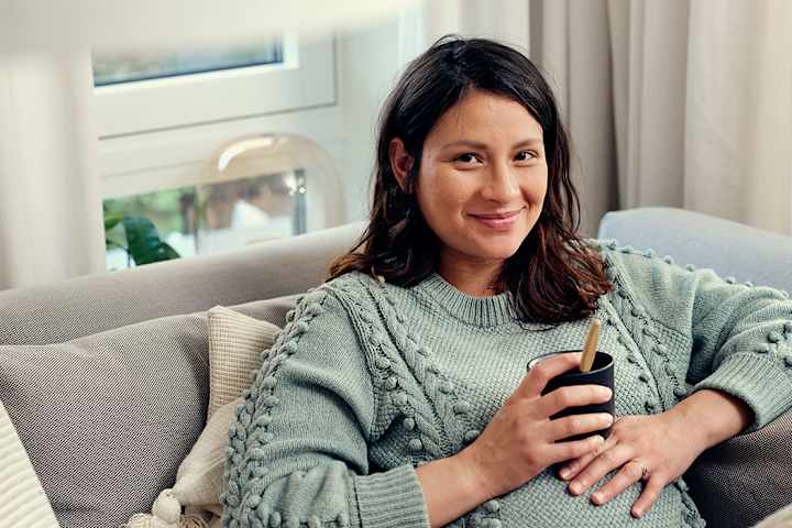 Tjej som sitter i soffan med en kopp