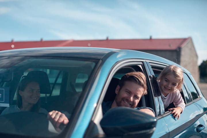 En mann og et barn titter ut av hvert sitt bilvindu. Det er varmt i lufta, og de smiler.