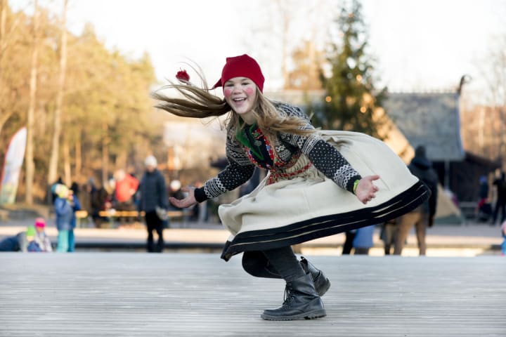 Foto av en nissejente som danse under Julemarkedet med nisselue og kjole.