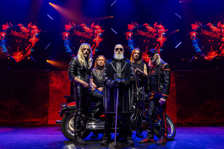 Foto av heavy-metal gruppen som står sammen på scenen og poser for kameraet.